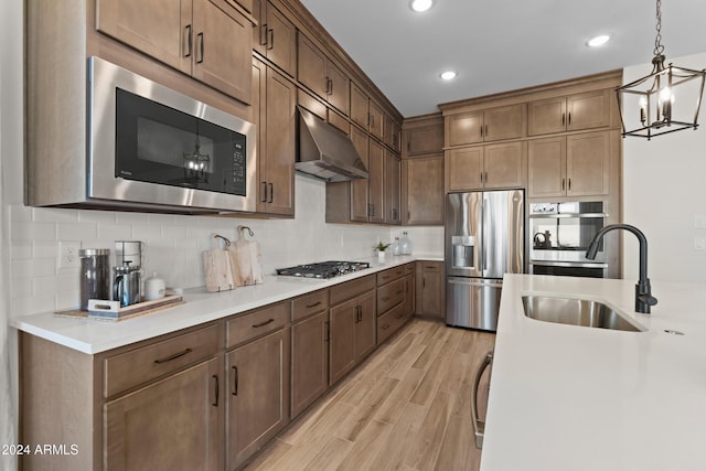 kitchen with sink, hanging light fixtures, appliances with stainless steel finishes, light hardwood / wood-style floors, and a chandelier