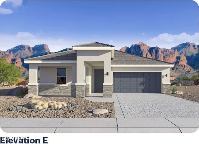 view of front of house featuring a garage, stone siding, a mountain view, and decorative driveway