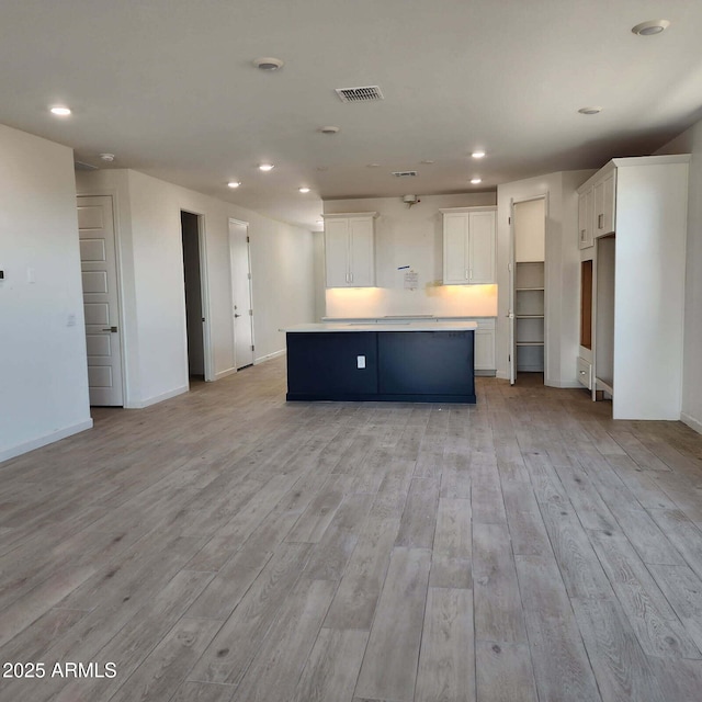 kitchen with light wood finished floors, visible vents, white cabinets, a center island, and recessed lighting