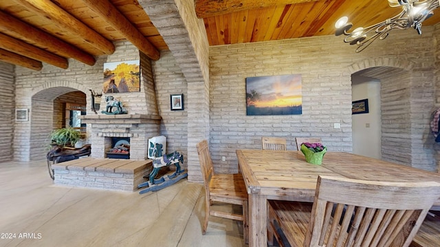 dining area featuring brick wall, a fireplace, and wood ceiling