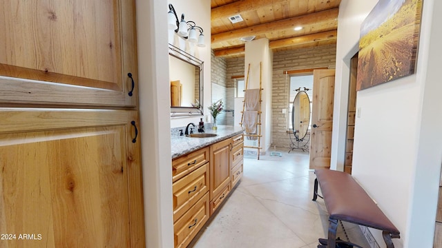 bathroom with beamed ceiling, tile floors, brick wall, wooden ceiling, and oversized vanity