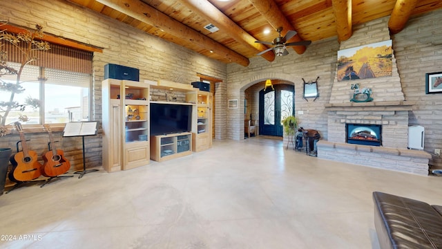 living room featuring ceiling fan, wood ceiling, a healthy amount of sunlight, and a stone fireplace