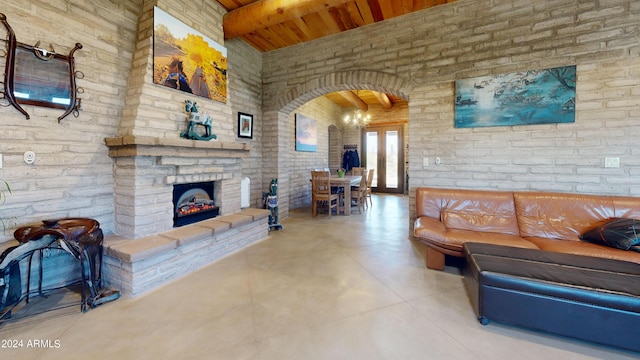 living room with brick wall, a stone fireplace, and wooden ceiling