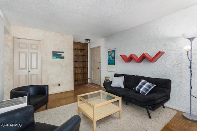 living room with built in features, wood-type flooring, and a textured ceiling