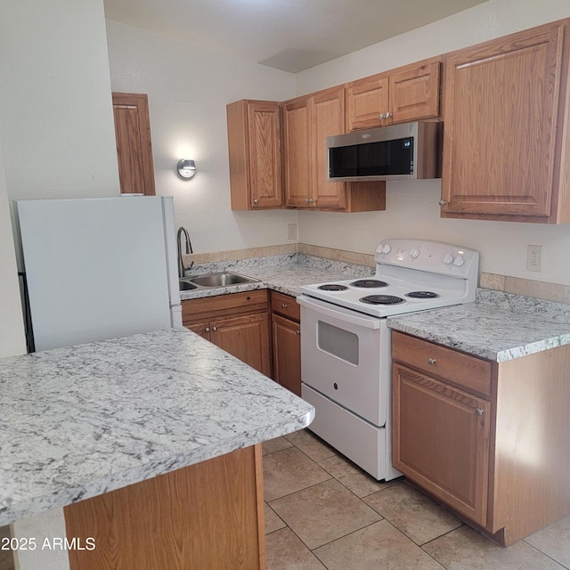 3645 N 69th Ave Unit 99, Phoenix, AZ 85033 - kitchen with white appliances, light countertops, light tile patterned floors, and brown cabinetry