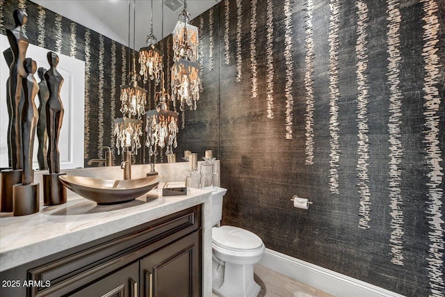 bathroom with vanity, toilet, and a notable chandelier