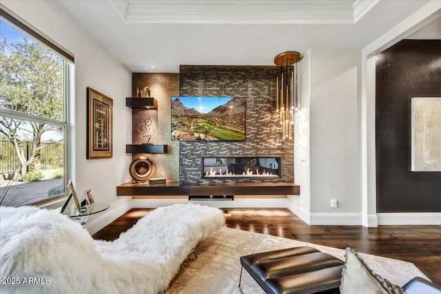 living room with crown molding, wood-type flooring, a fireplace, and a tray ceiling