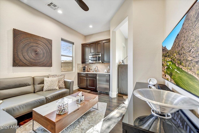 living room featuring dark wood-type flooring, ceiling fan, and bar