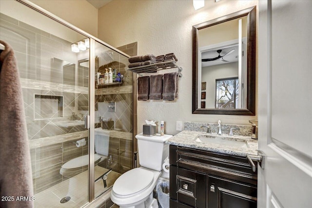 bathroom with a shower with door, vanity, and toilet