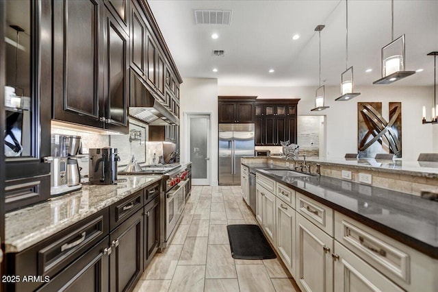 kitchen with sink, dark brown cabinets, high quality appliances, decorative backsplash, and decorative light fixtures