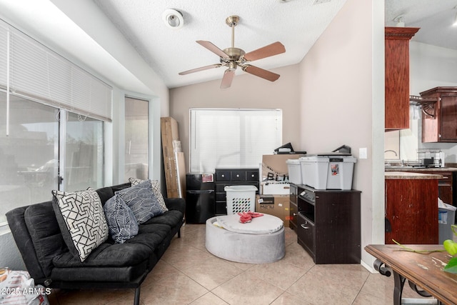 living room with vaulted ceiling, ceiling fan, light tile patterned floors, and a textured ceiling