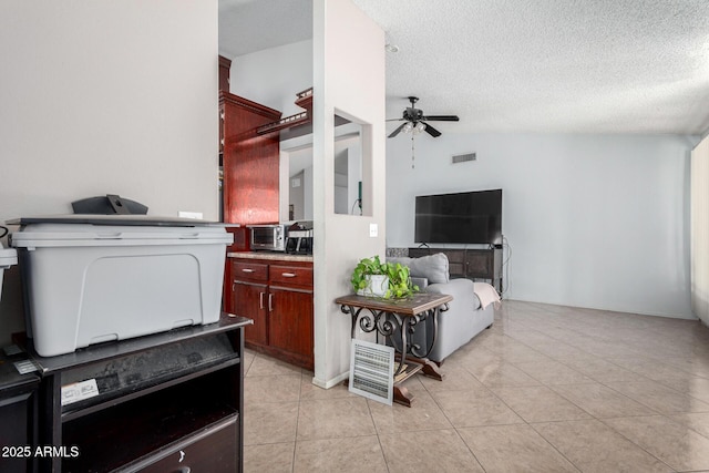 interior space featuring ceiling fan, light tile patterned floors, vaulted ceiling, and a textured ceiling