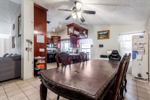 dining space featuring ceiling fan, vaulted ceiling, light tile patterned flooring, and a textured ceiling