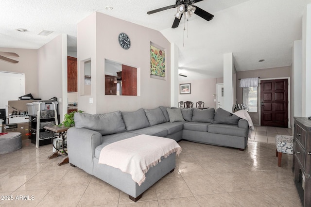 tiled living room featuring ceiling fan, vaulted ceiling, and a textured ceiling