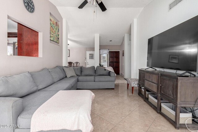 tiled living room with ceiling fan and vaulted ceiling