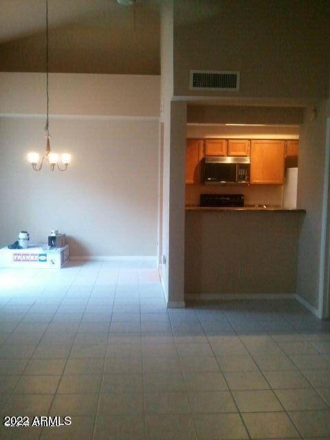 kitchen featuring refrigerator, decorative light fixtures, a high ceiling, a notable chandelier, and tile patterned floors