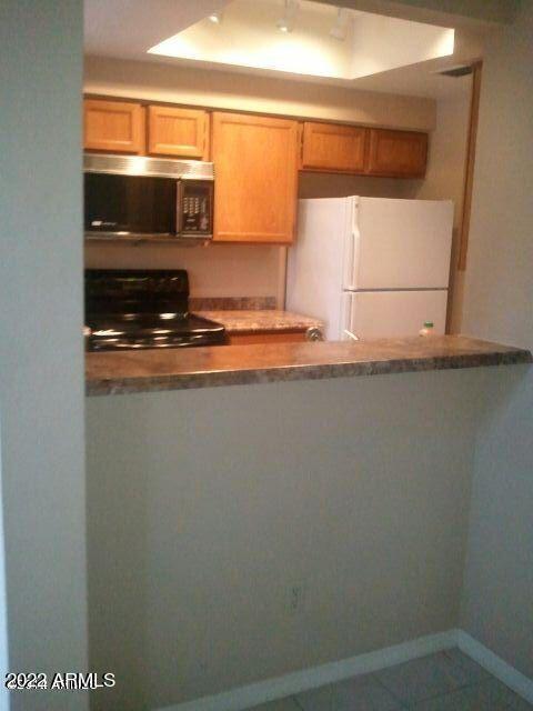 kitchen featuring tile patterned flooring, white fridge, and electric range