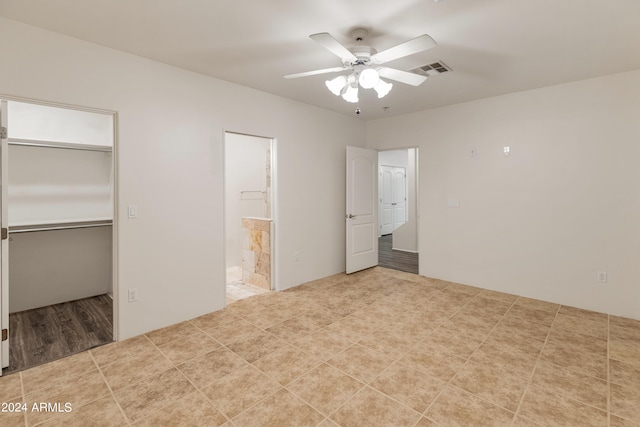 unfurnished bedroom featuring ceiling fan, ensuite bathroom, a closet, and a spacious closet