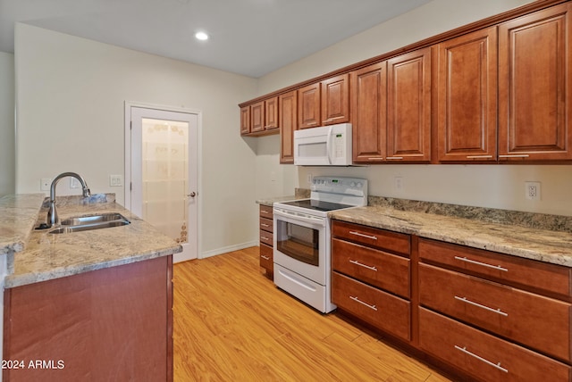 kitchen with sink, white appliances, light stone counters, and light hardwood / wood-style flooring