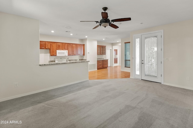 unfurnished living room with light carpet and ceiling fan