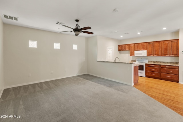 kitchen with kitchen peninsula, light stone countertops, sink, white appliances, and ceiling fan