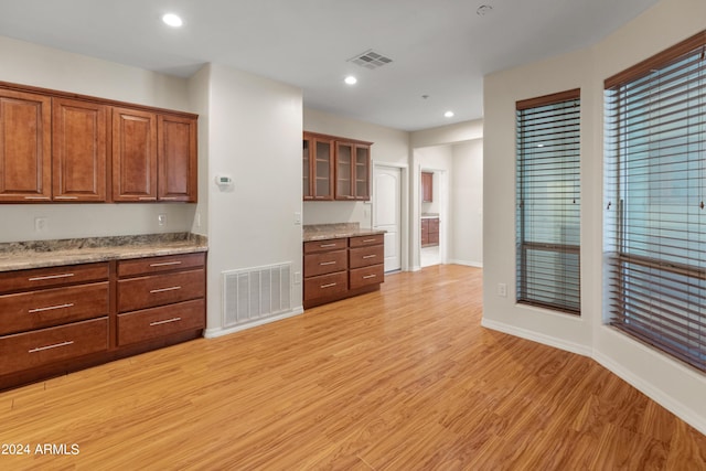 kitchen featuring light hardwood / wood-style flooring, built in desk, and light stone counters