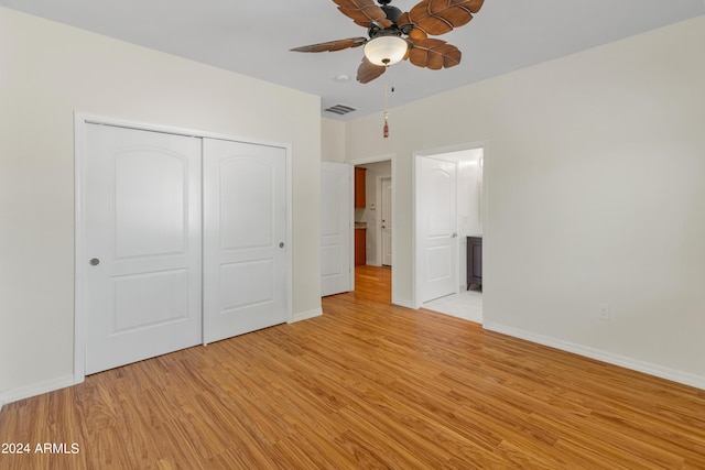 unfurnished bedroom featuring ceiling fan, light wood-type flooring, a closet, and ensuite bathroom