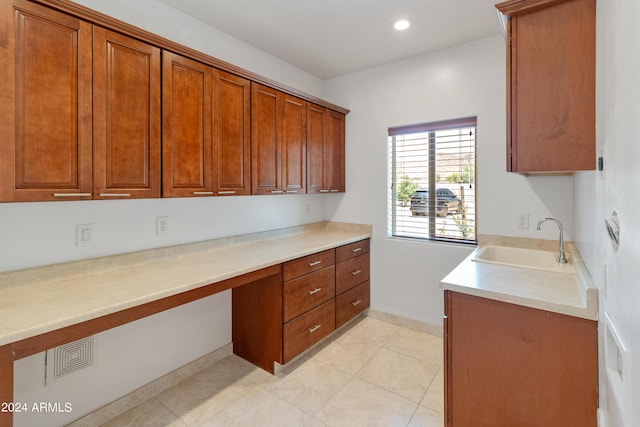 kitchen featuring sink, built in desk, and light tile patterned flooring