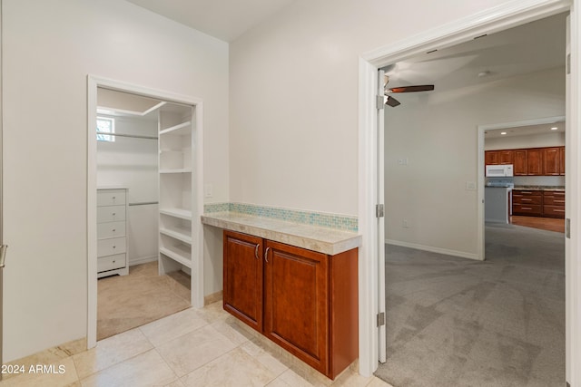 spacious closet with light carpet and ceiling fan