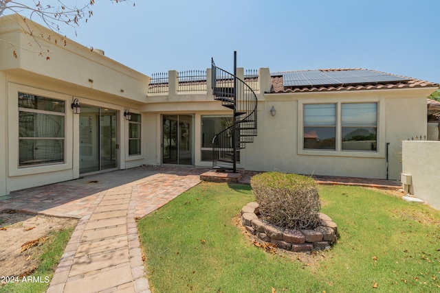 rear view of property with a patio area, solar panels, and a yard