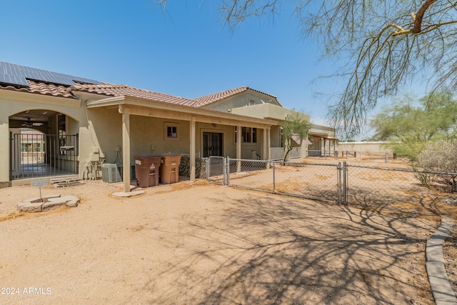 back of house featuring central AC unit and solar panels