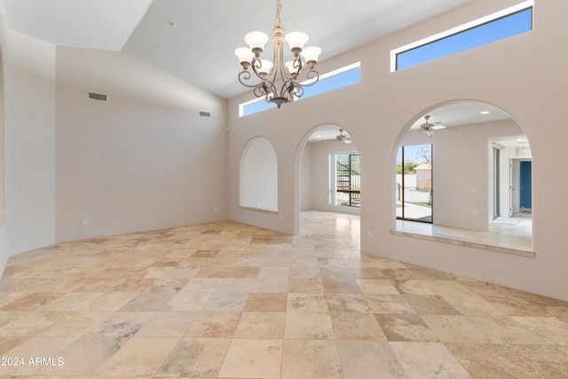 empty room featuring ceiling fan with notable chandelier and high vaulted ceiling