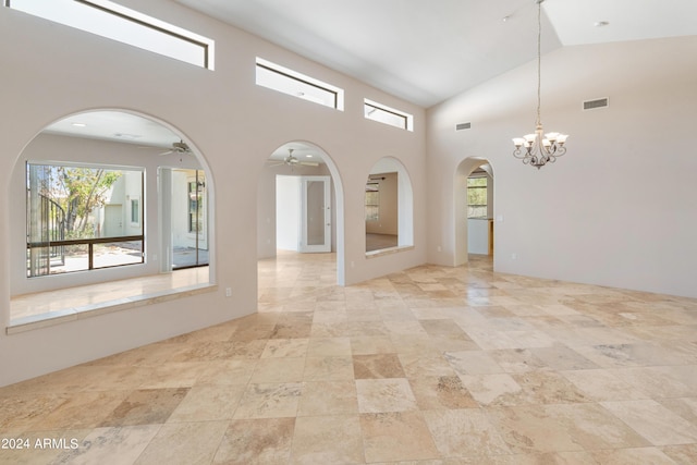 spare room featuring ceiling fan with notable chandelier, plenty of natural light, and vaulted ceiling