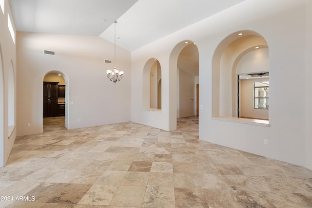 spare room with high vaulted ceiling and an inviting chandelier