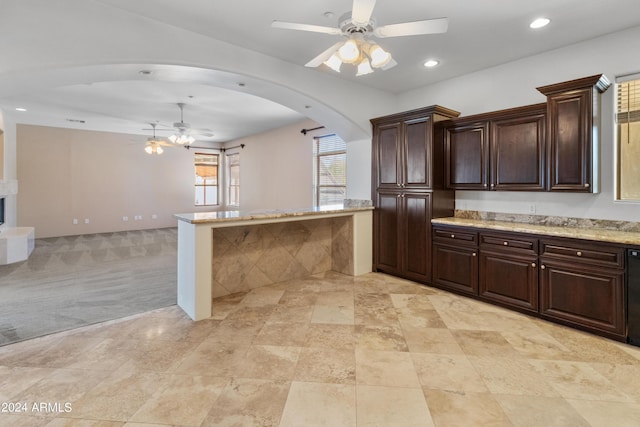 kitchen featuring black dishwasher, light stone counters, ceiling fan, light carpet, and dark brown cabinets