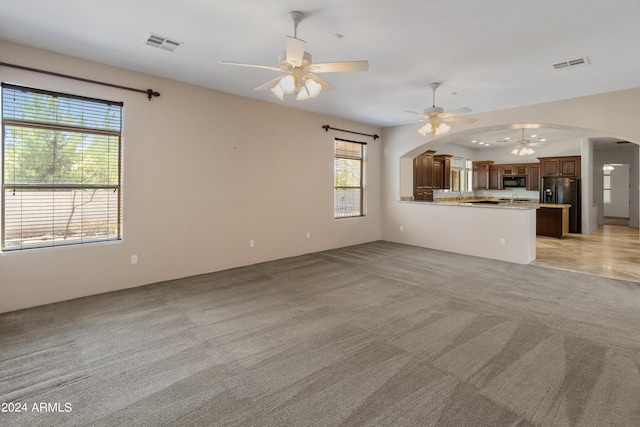 unfurnished living room featuring ceiling fan and light colored carpet