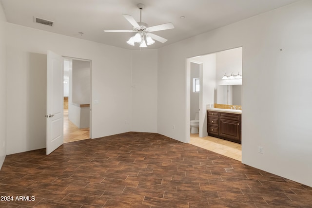 unfurnished bedroom featuring sink, dark wood-type flooring, ensuite bathroom, and ceiling fan