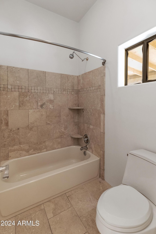 bathroom with tile patterned floors, toilet, and tiled shower / bath