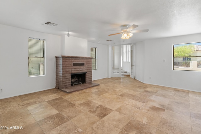 unfurnished living room featuring ceiling fan and a fireplace