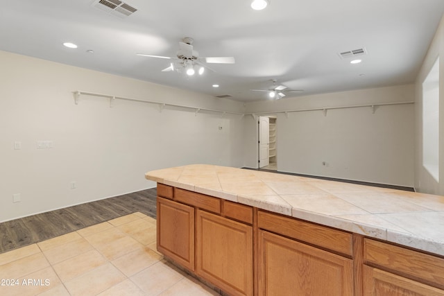 kitchen with ceiling fan, light tile patterned flooring, and tile counters