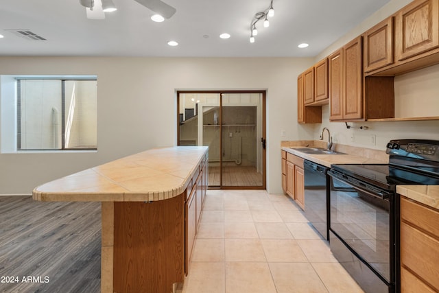 kitchen featuring light tile patterned floors, sink, ceiling fan, black appliances, and tile countertops