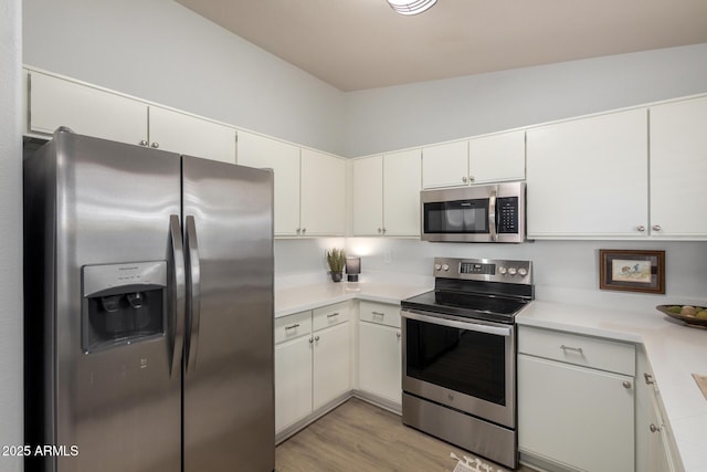 kitchen featuring appliances with stainless steel finishes, light countertops, light wood-style flooring, and white cabinetry