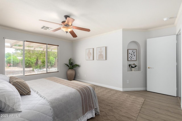 bedroom featuring wood finished floors, crown molding, baseboards, and a ceiling fan