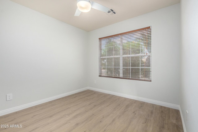 spare room featuring light wood-type flooring, ceiling fan, and baseboards