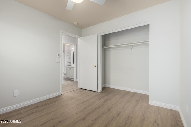 unfurnished bedroom featuring wood finished floors, a closet, baseboards, and a ceiling fan