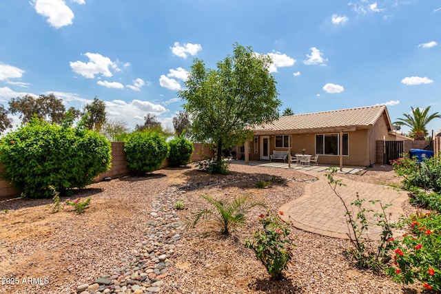back of house with a fenced backyard, stucco siding, a tiled roof, and a patio