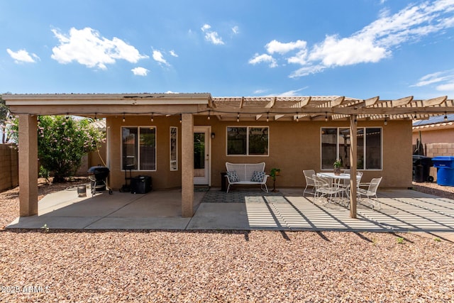 rear view of property featuring a pergola, fence, stucco siding, and a patio