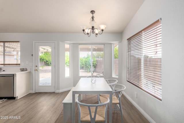 dining room with wood finished floors, healthy amount of natural light, a chandelier, and baseboards