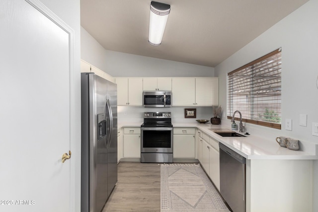 kitchen with stainless steel appliances, a sink, lofted ceiling, light countertops, and light wood-type flooring