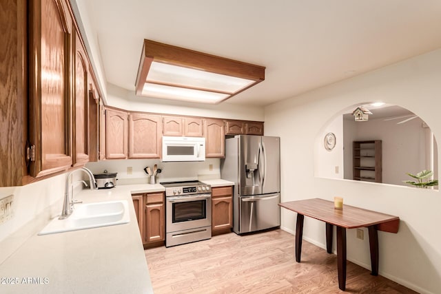 2105 S Zinnia Ave Unit 468, Mesa, AZ 85209 - kitchen featuring stainless steel appliances, light countertops, light wood-style flooring, arched walkways, and brown cabinets